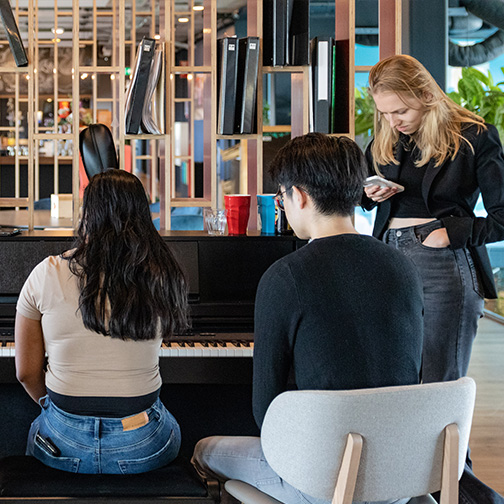 Een collega speelt piano op kantoor bij TOPdesk terwijl andere collega’s luisteren.